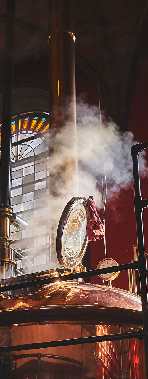 Brewery worker near copper brewing vat
