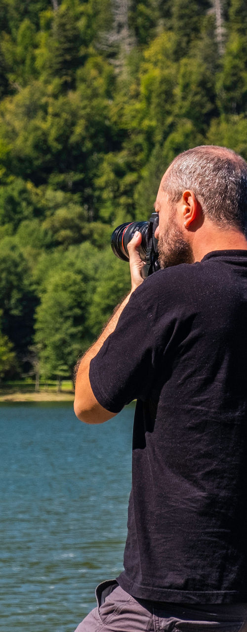 Man photographing lake surrounded by forest