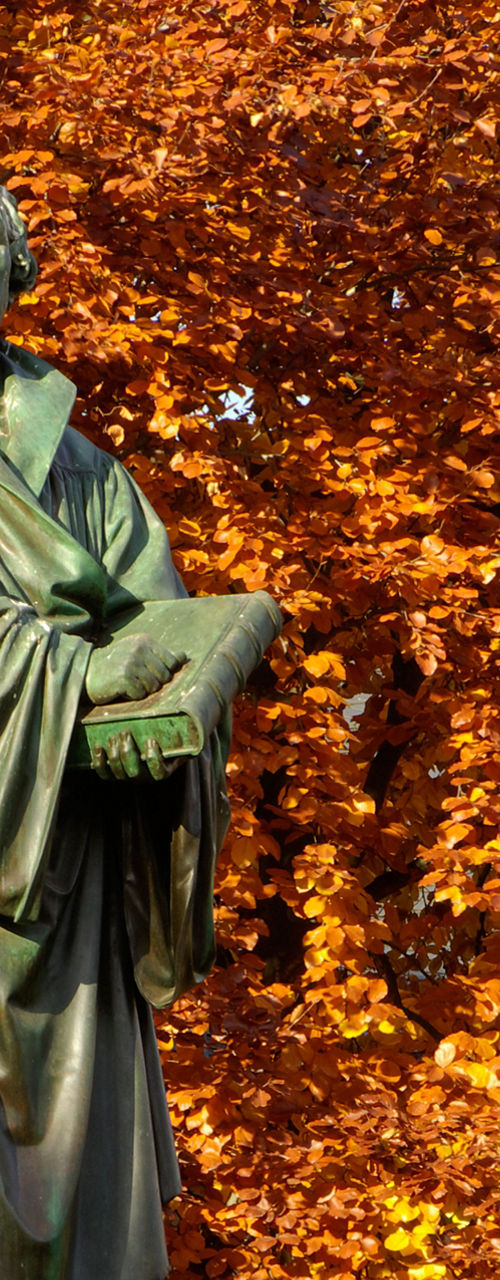 Bronze statue amidst autumn foliage