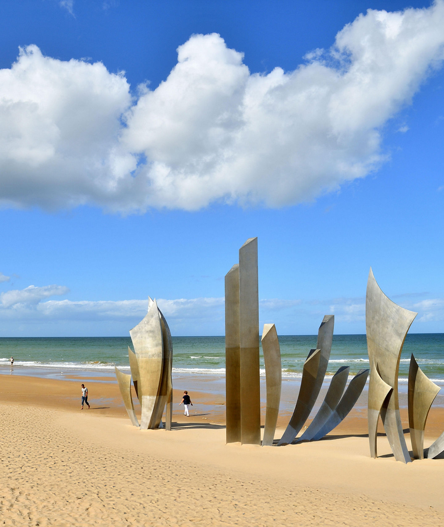 Modern sculpture on sandy beach under blue sky