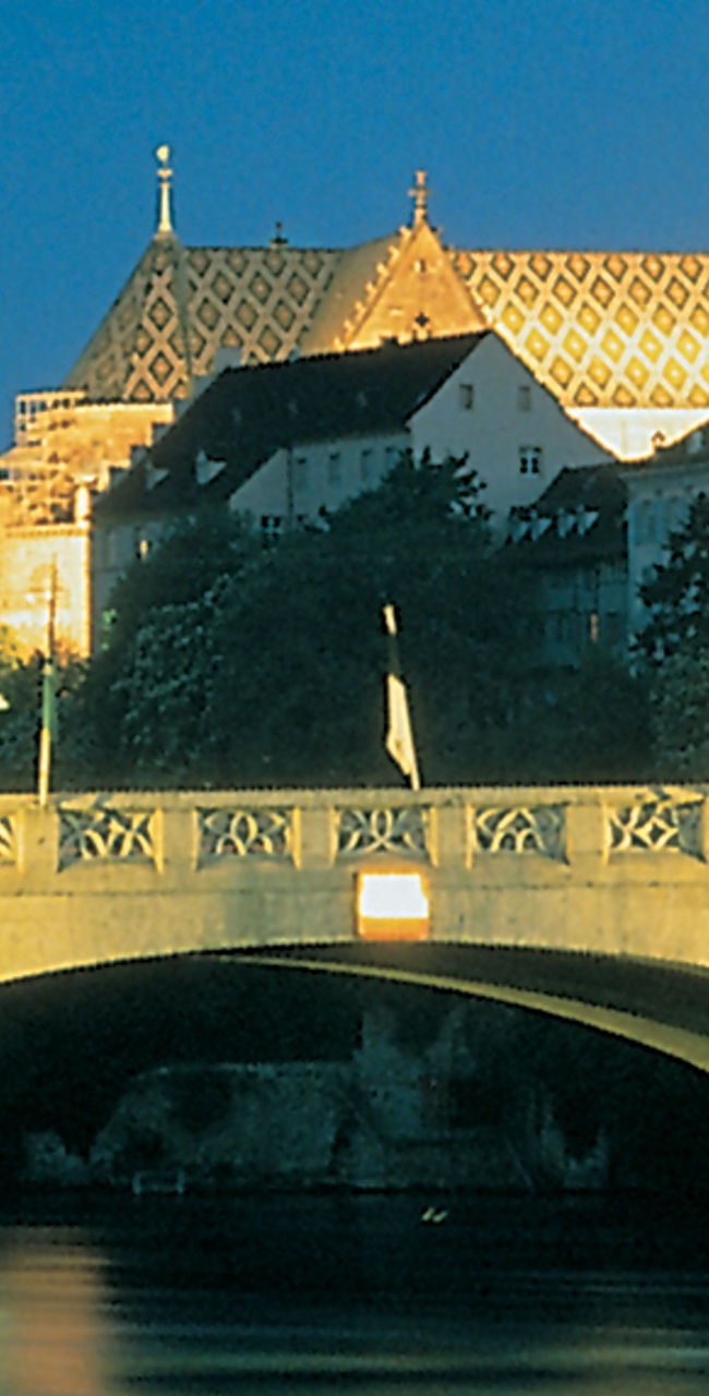 Illuminated bridge and Basel Cathedral at night