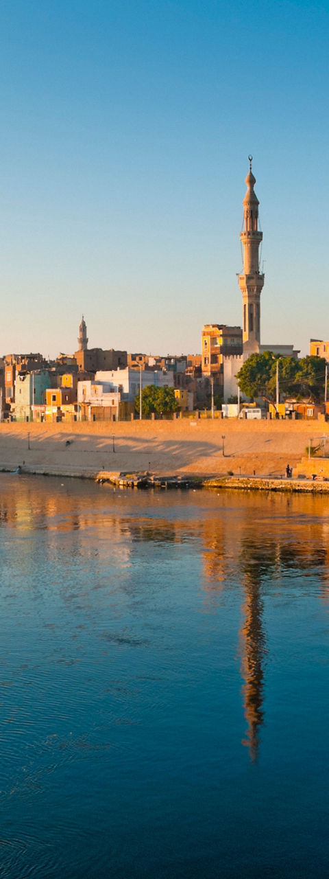 Scenic riverside town with mosque at sunrise