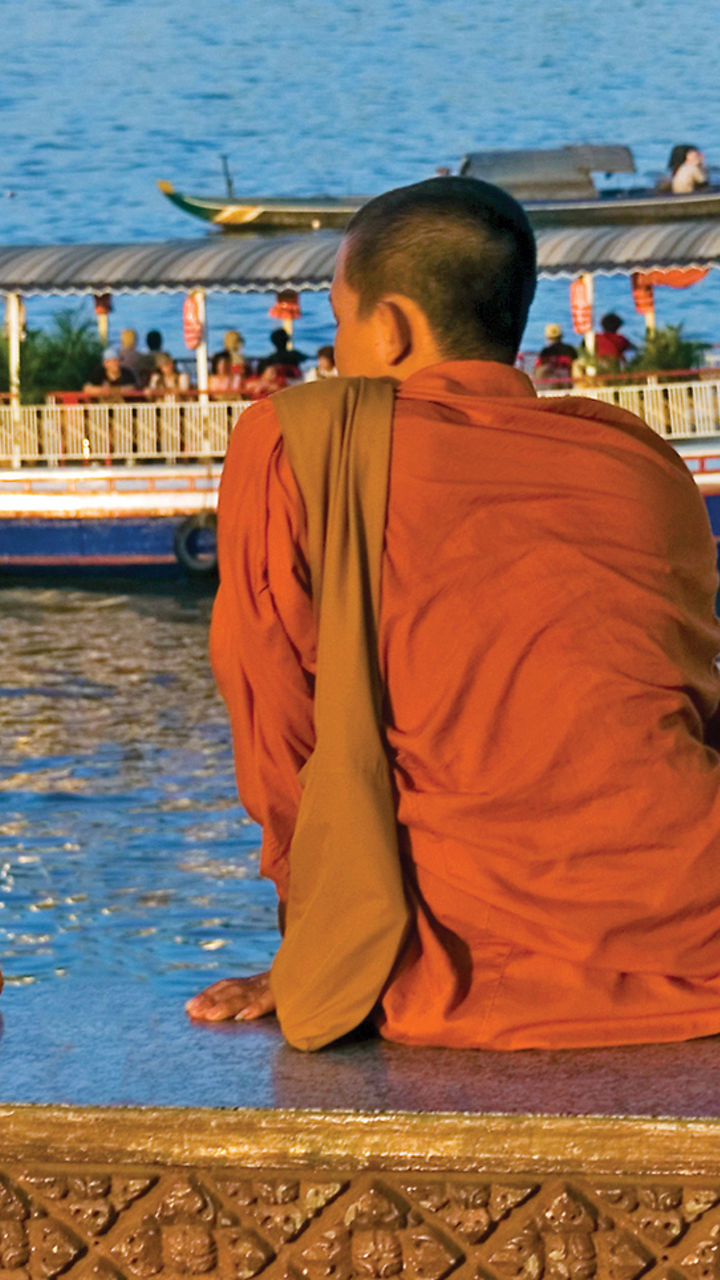 Monks overlooking river with tourist boat