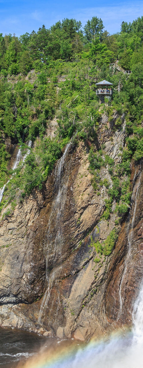 Large waterfall with rainbow and lush green forest