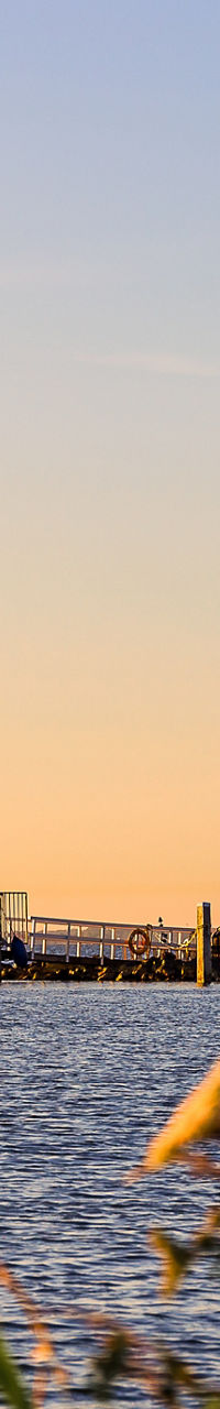 Scenic lighthouse by calm waterfront at sunset