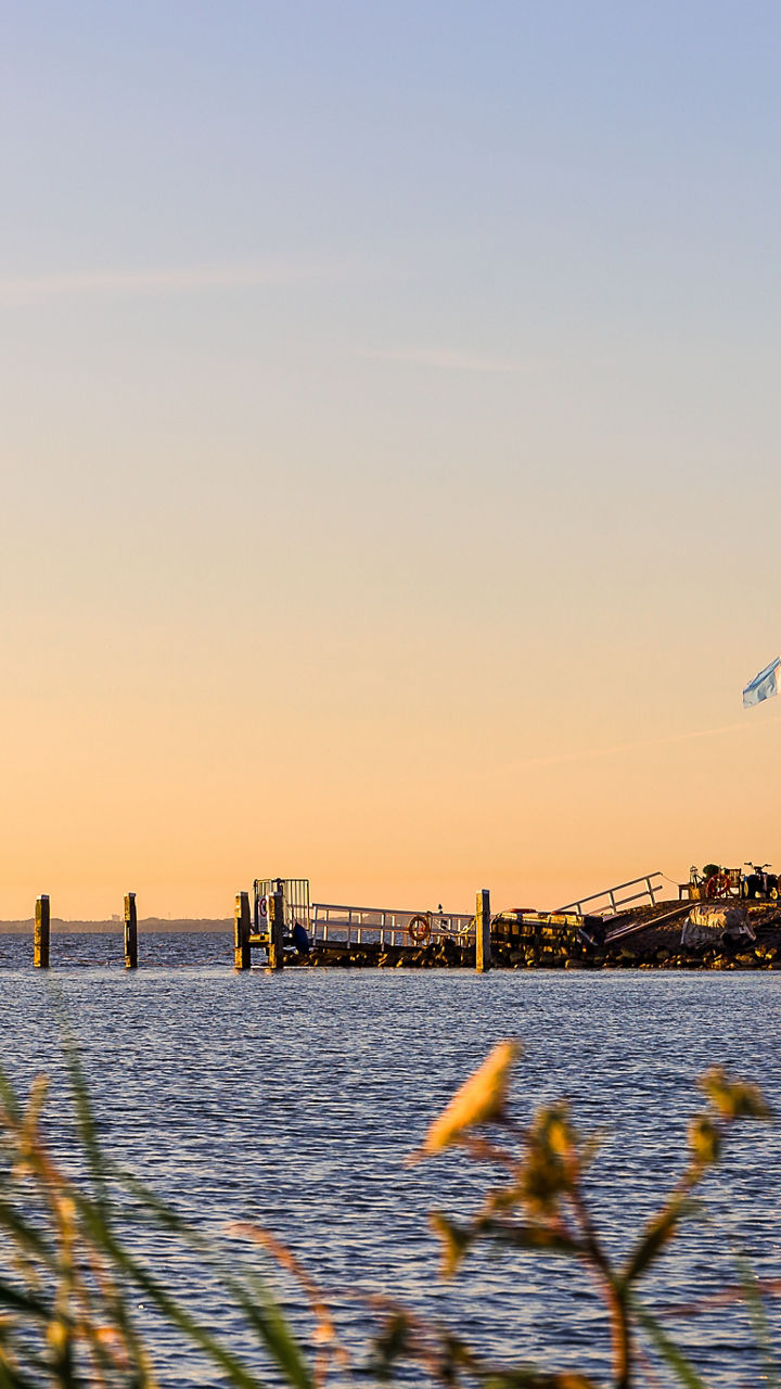 Scenic lighthouse by calm waterfront at sunset