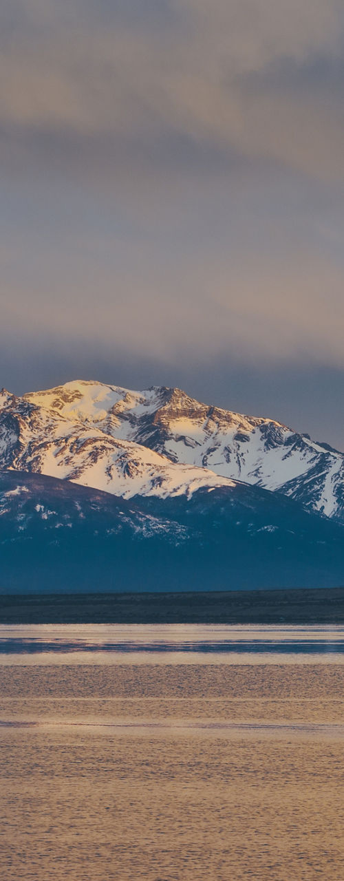 Snow-capped mountains at sunset over calm water