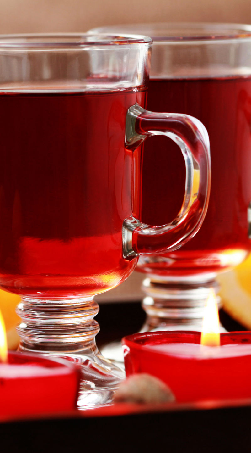 Warm spiced drink with candles and oranges