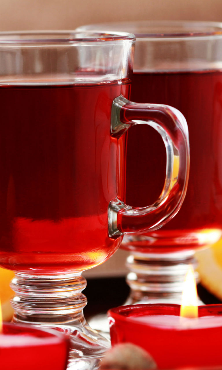 Warm spiced drink with candles and oranges