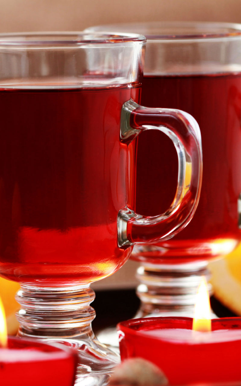 Warm spiced drink with candles and oranges