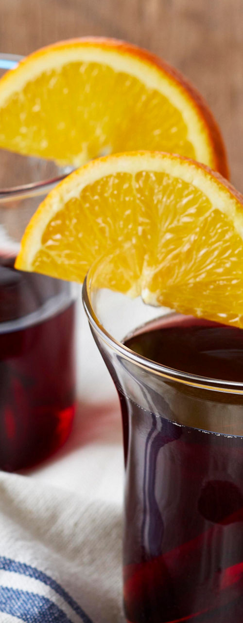 Two glass mugs of mulled wine with orange slices