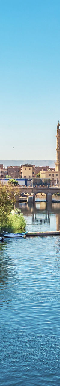 Riverside cityscape with boats and minaret