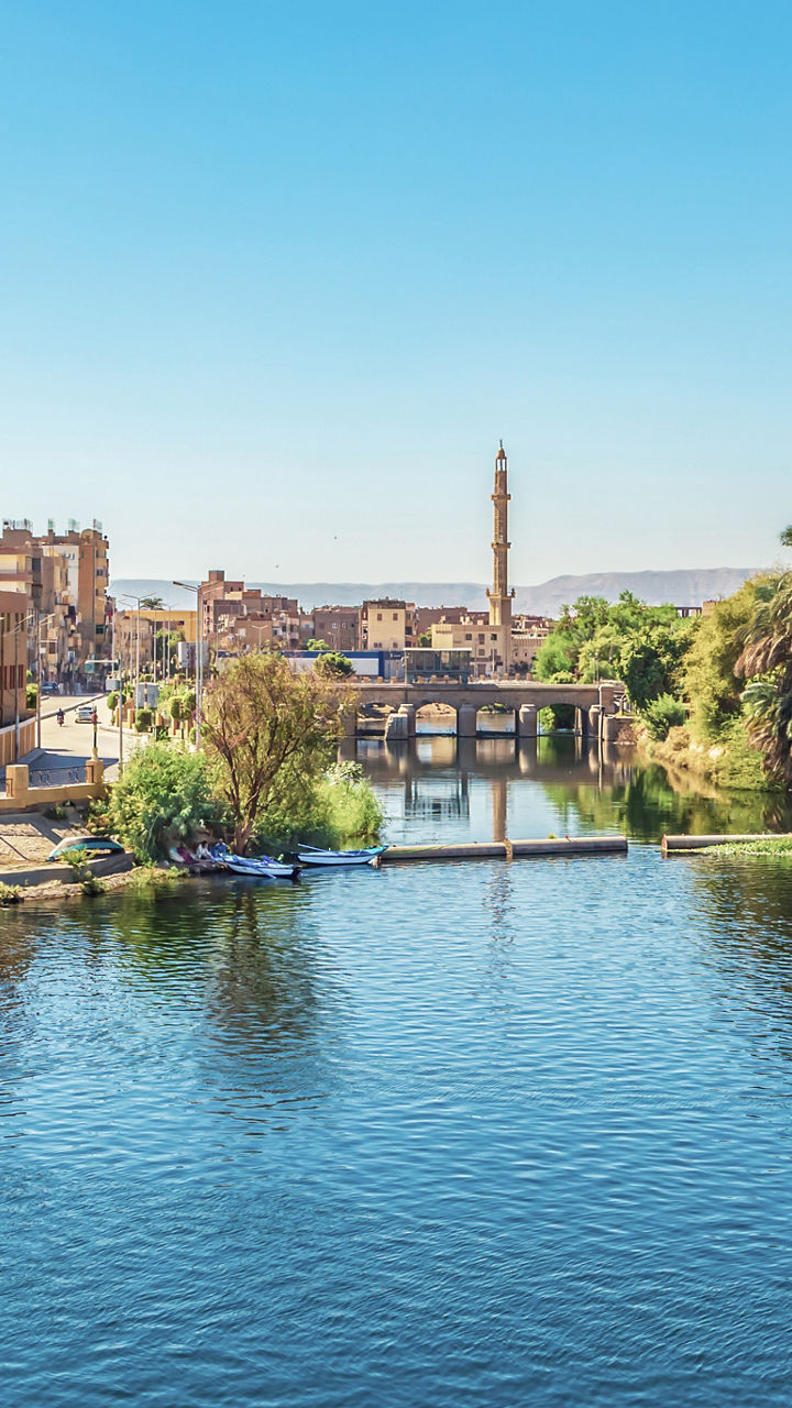 Riverside cityscape with boats and minaret