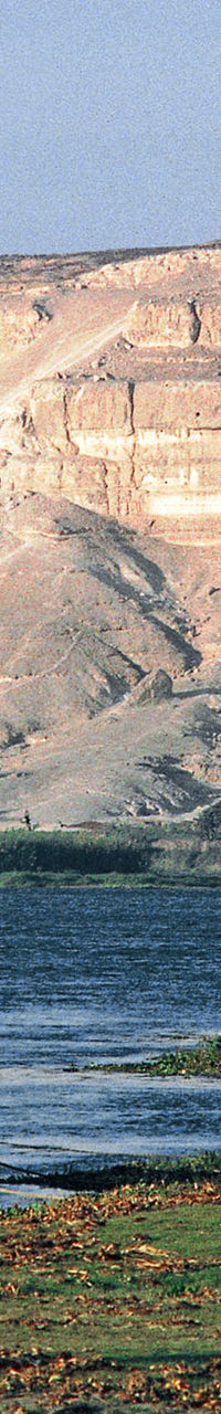 Sailboat moored on riverbank near cliffs