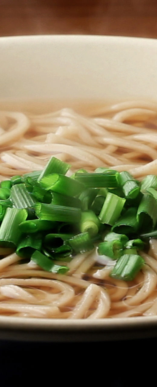 Steaming bowl of soba noodles with garnish