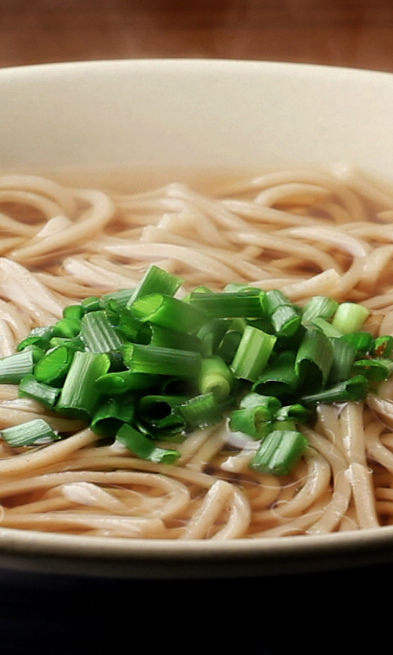 Steaming bowl of soba noodles with garnish