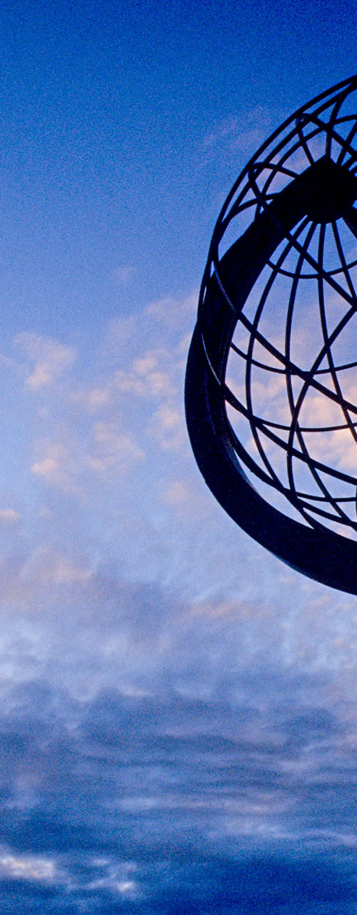 Metal globe sculpture at sunset