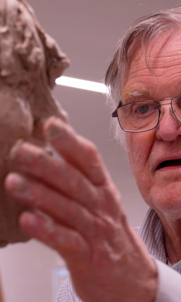 Sculptor shaping clay bust in studio