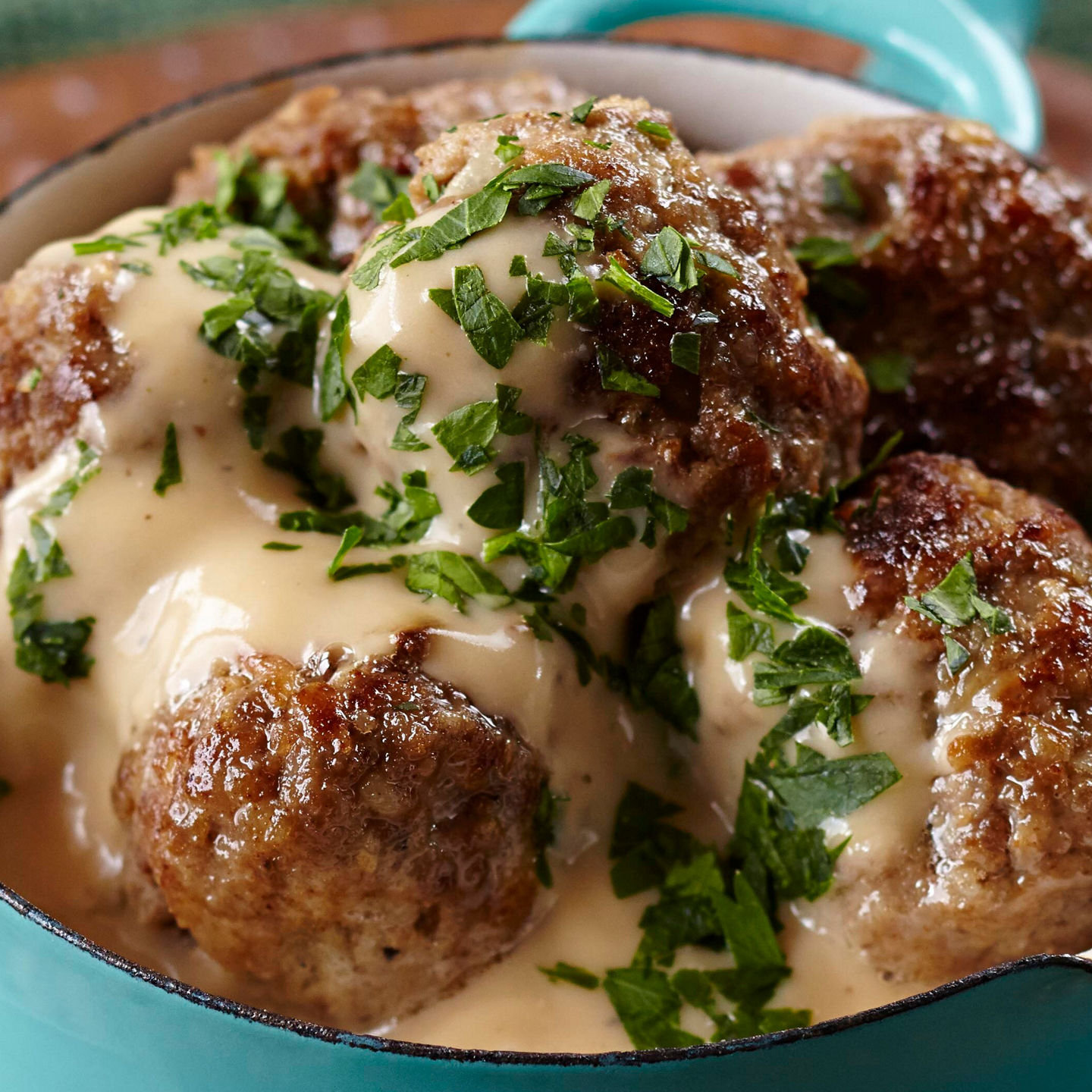 Meatballs in creamy sauce in blue bowl