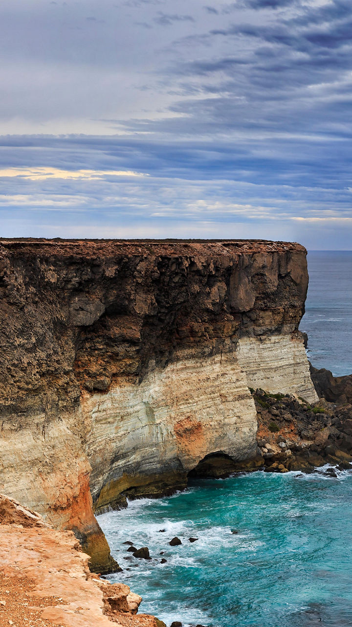 Dramatic coastal cliff under cloudy sky