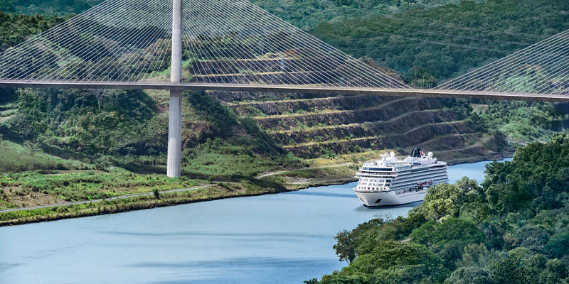 Cruise ship under cable-stayed bridge in lush valley