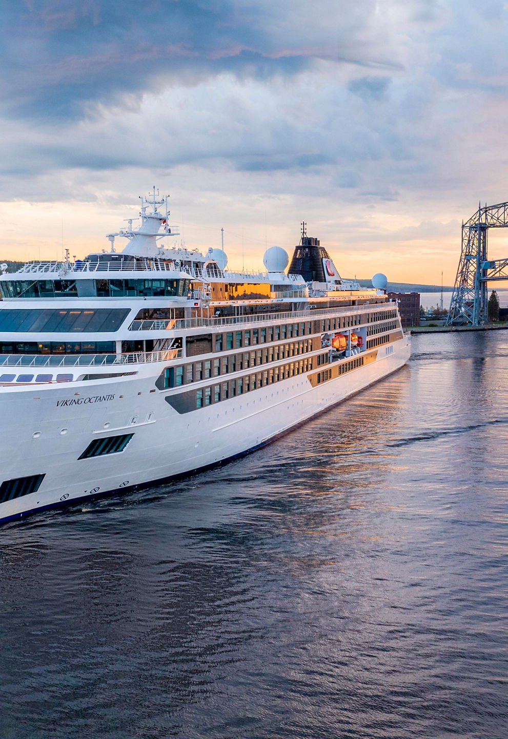 Luxury cruise ship near iconic bridge at sunset