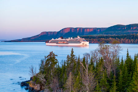 Cruise ship near scenic forest coastline