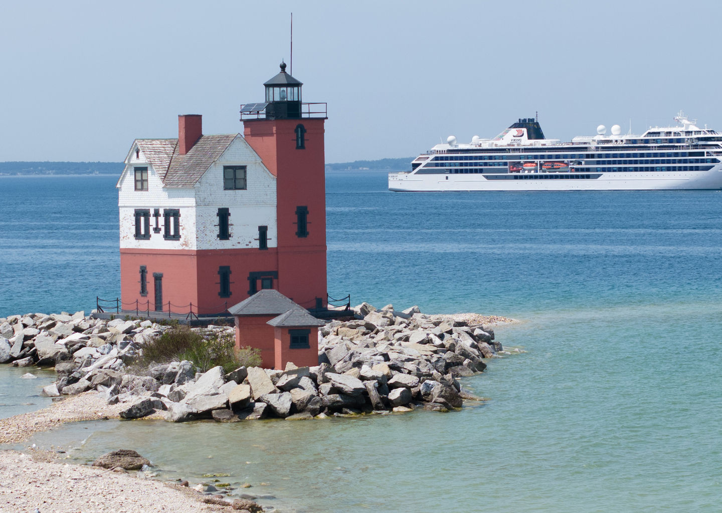 Red lighthouse with cruise ship in background