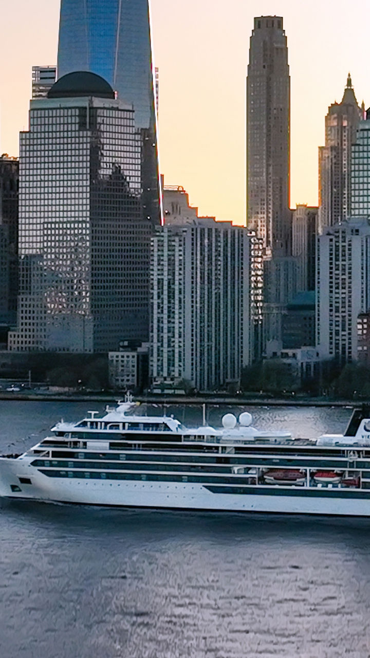 Cruise ship near Manhattan skyline at sunset
