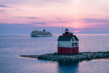 Lighthouse at sunset with cruise ship