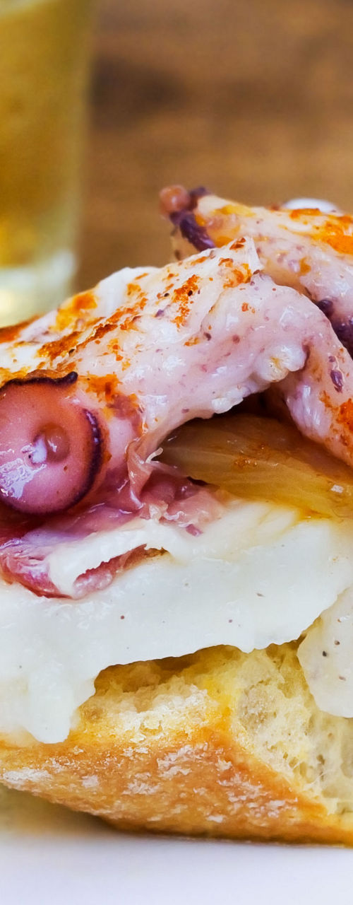 Octopus tapas with white wine glass