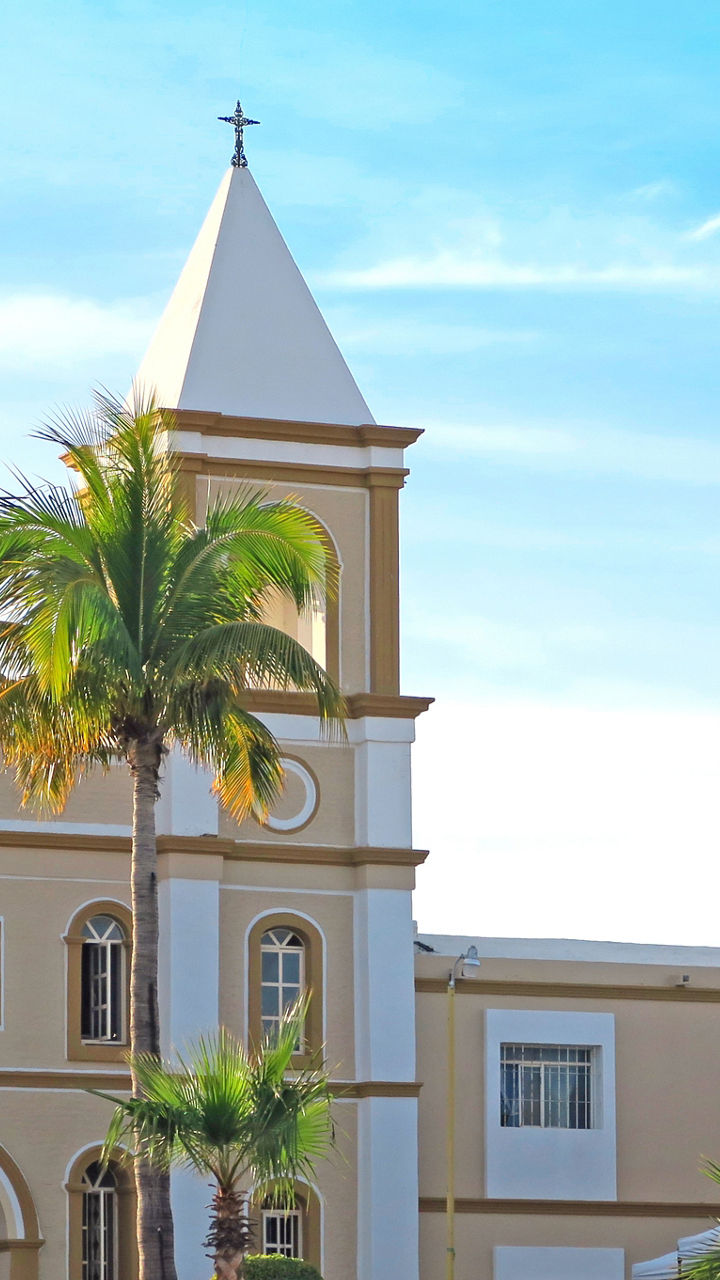 Historic church with palm trees under blue sky