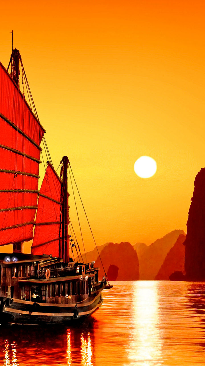 Traditional red sailboat at sunset on calm waters