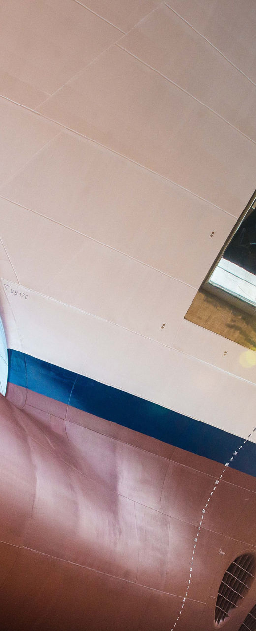 Two people observe large ship in dry dock