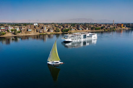 Sailboat and cruise ship on calm river