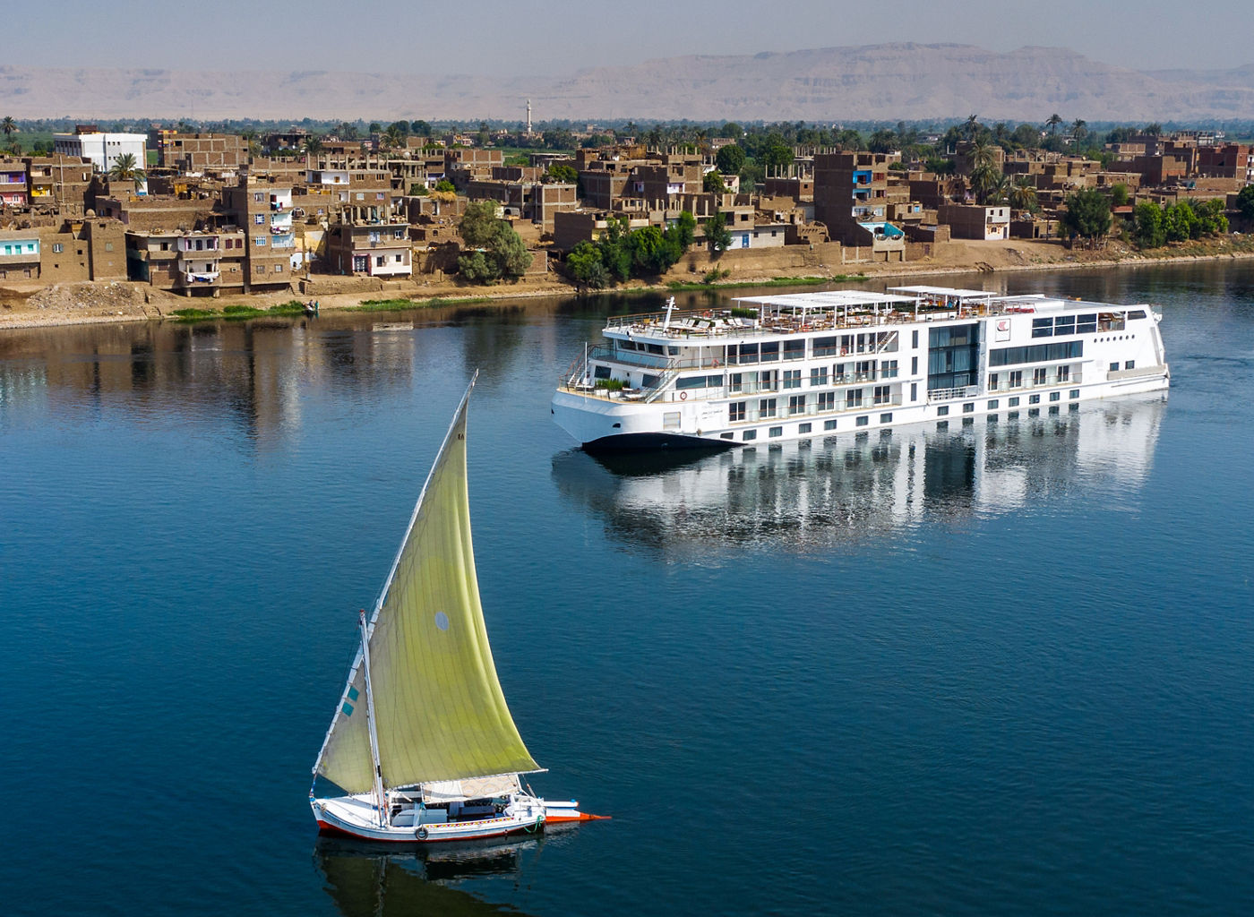 Sailboat and cruise ship on calm river