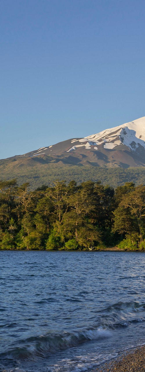 Snow-capped volcano by serene lakeshore