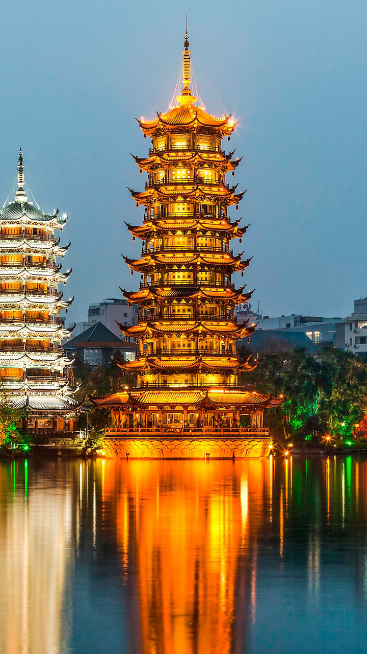 Illuminated twin pagodas by serene lake