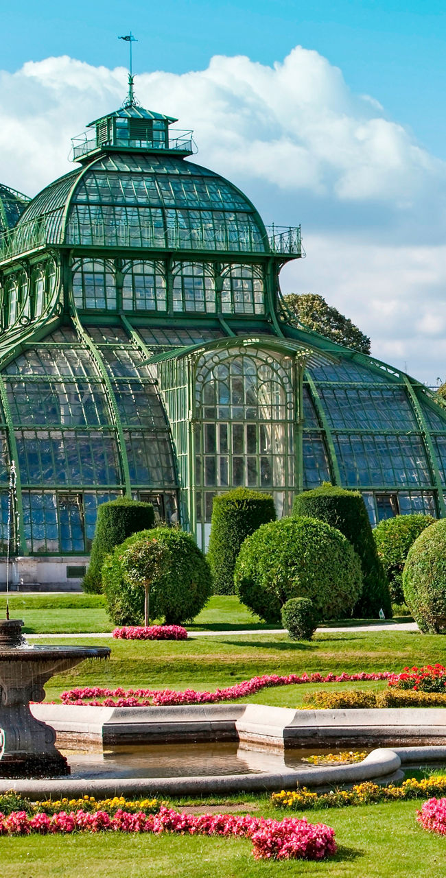 Historic glass greenhouse in lush garden