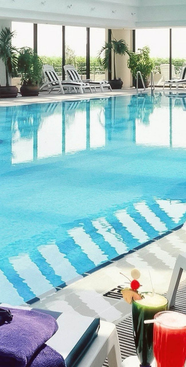 Indoor pool with glass ceiling and lounge chairs