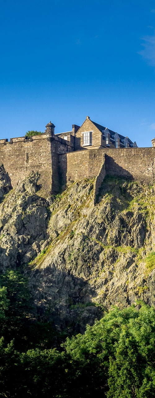 Edinburgh Castle on rocky hilltop under blue sky