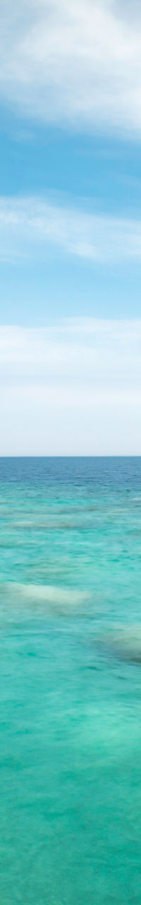 Rock formation by turquoise waters under blue sky