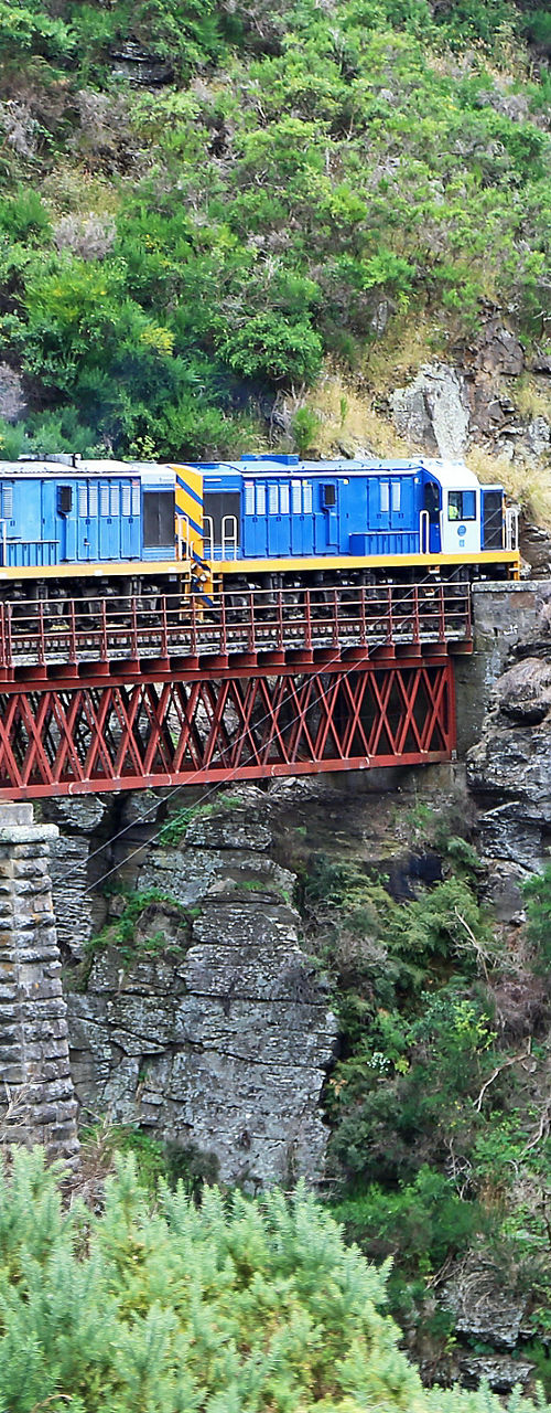 Colorful passenger train crossing mountain bridge