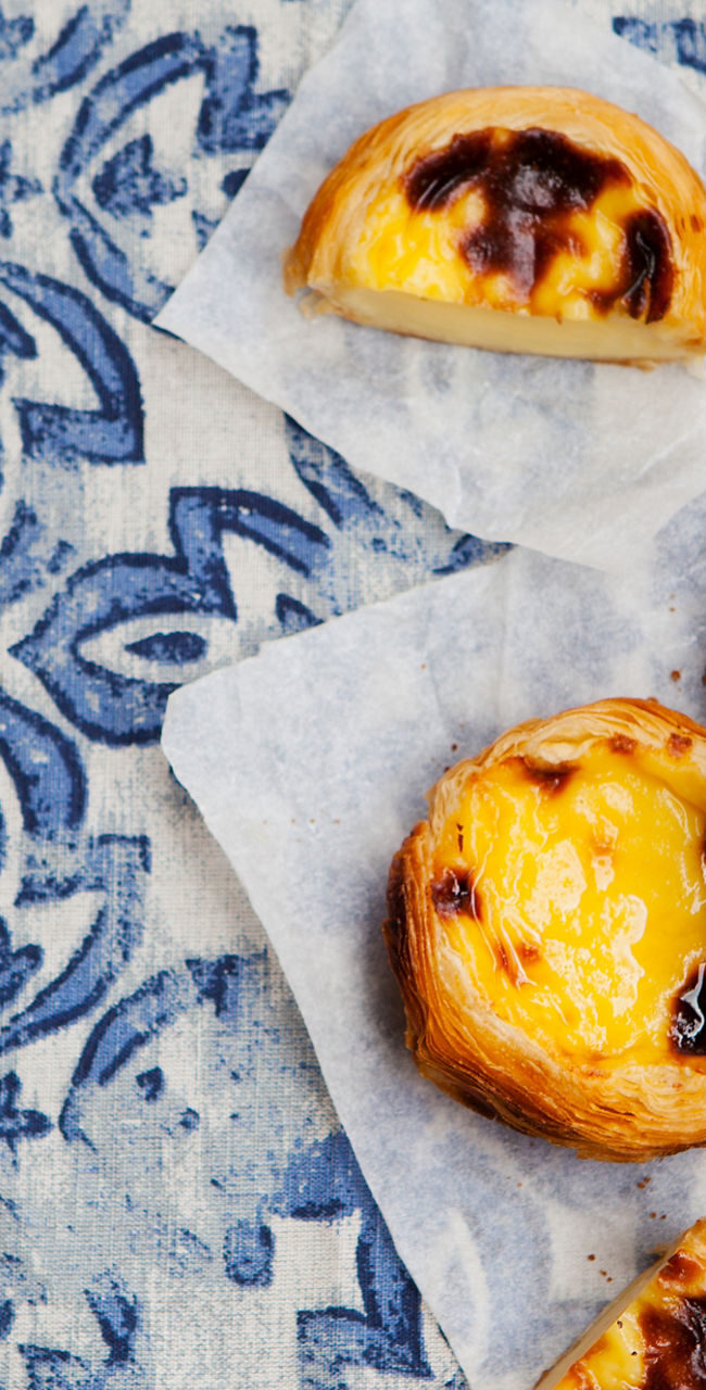 Portuguese custard tarts with coffee on patterned table