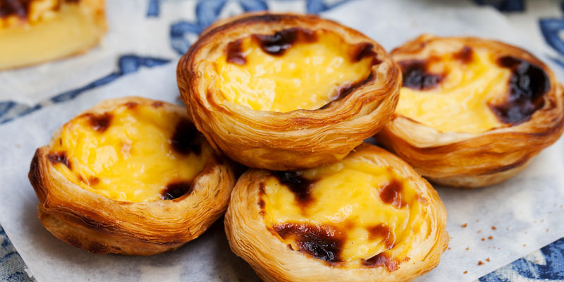Golden Portuguese custard tarts on paper