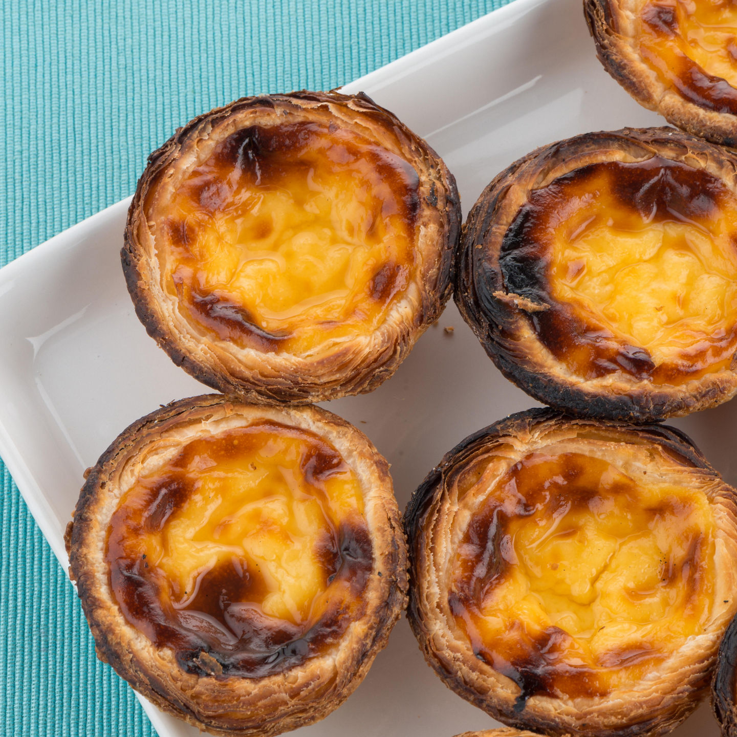 Golden Portuguese custard tarts on white plate