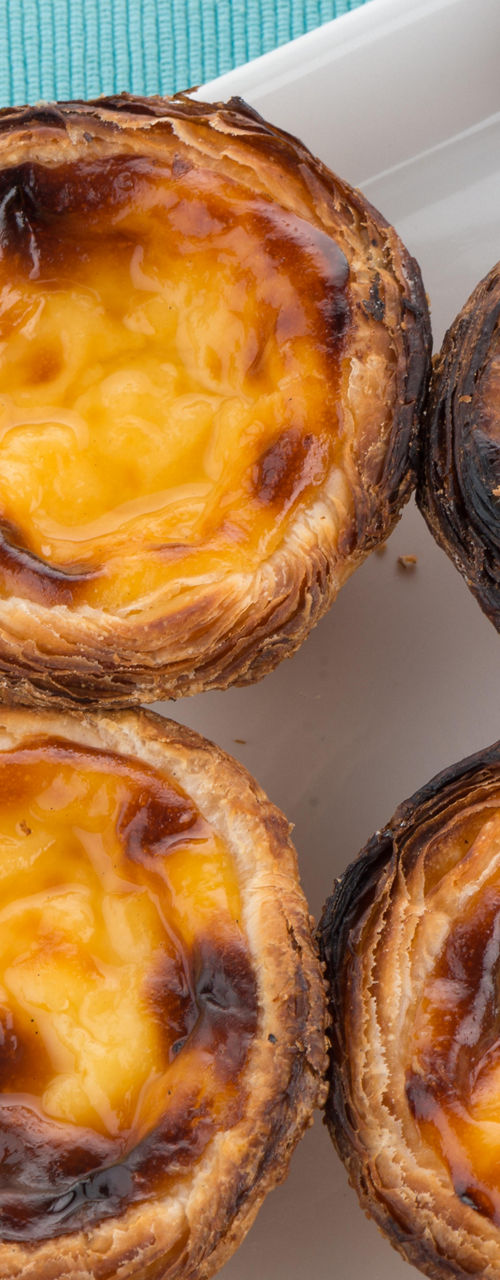 Golden Portuguese custard tarts on white plate