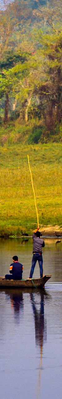 Three people fishing on calm river
