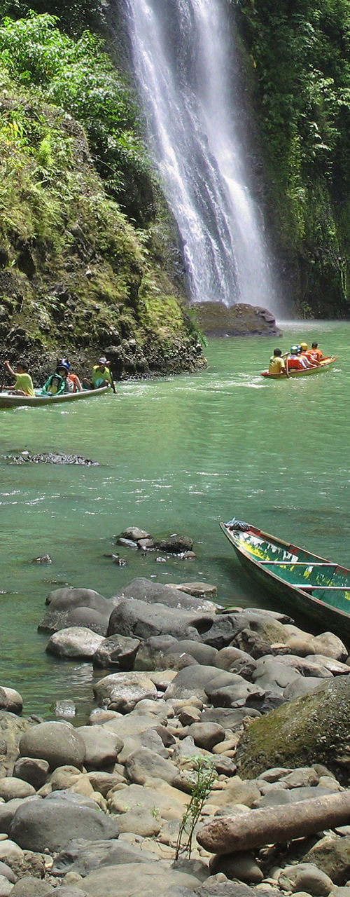 Scenic waterfall with boats in lush forest