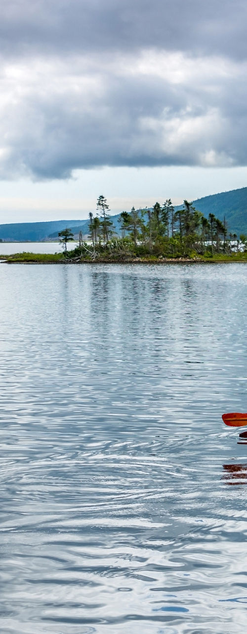 Solo kayaker on serene lake with island